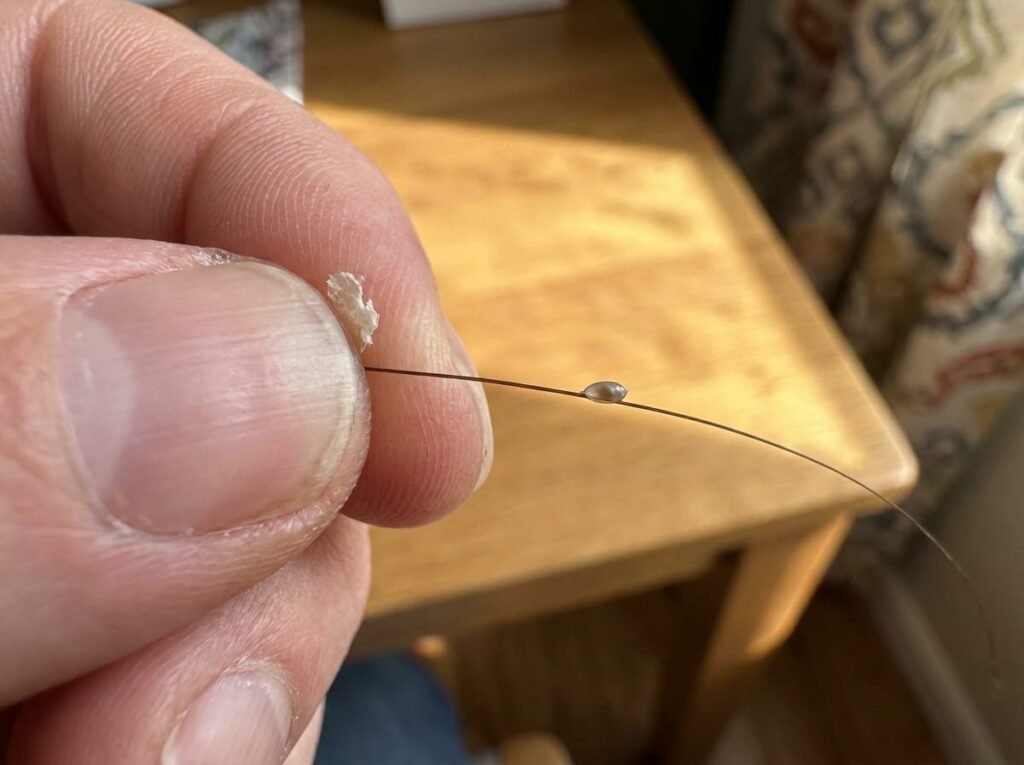 Manos de un progenitor realizando la prueba del tacto en un mechón de pelo para diferenciar caspa y liendres